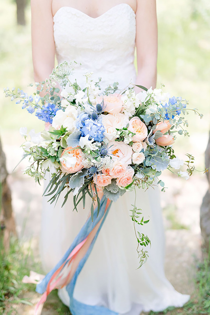 Bride holding blue & peach flower bouquet