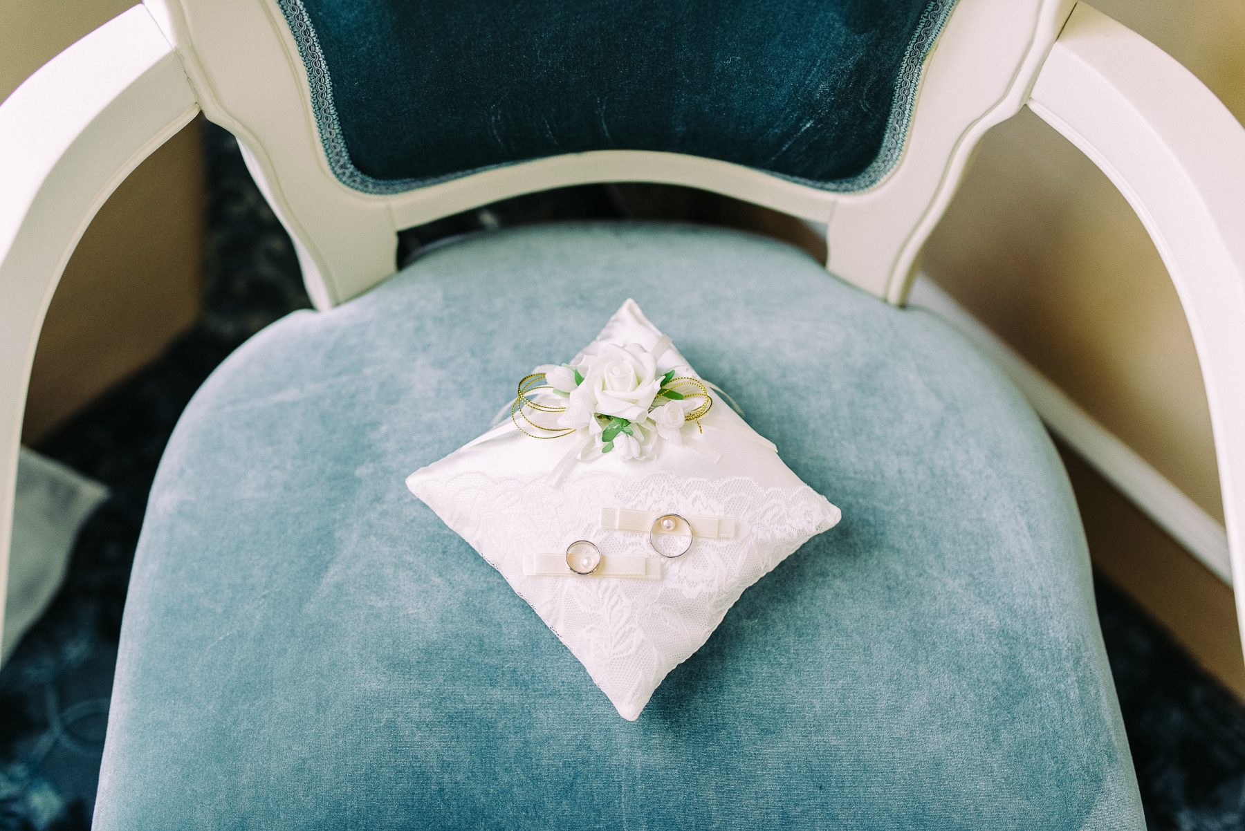 white pillow on white wooden armchair with blue cushion