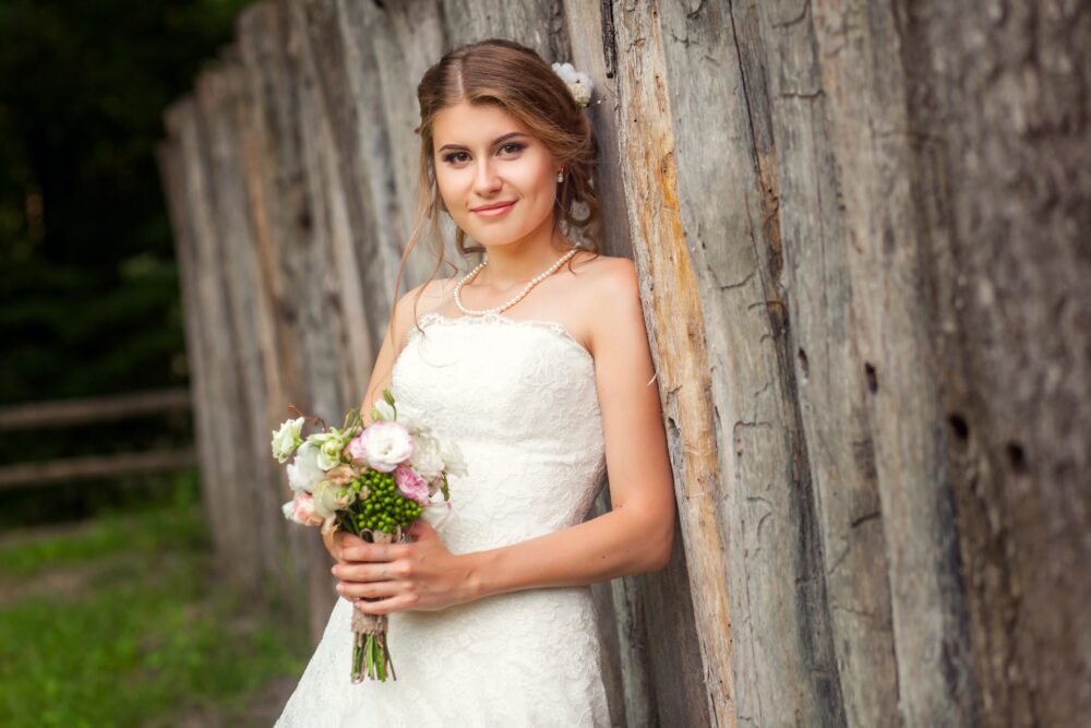 Rustic bride leaning on a wood fence