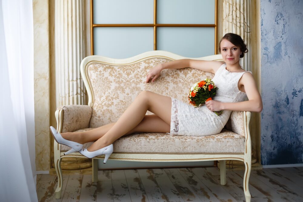 Bride sitting on a couch in a short lace dress