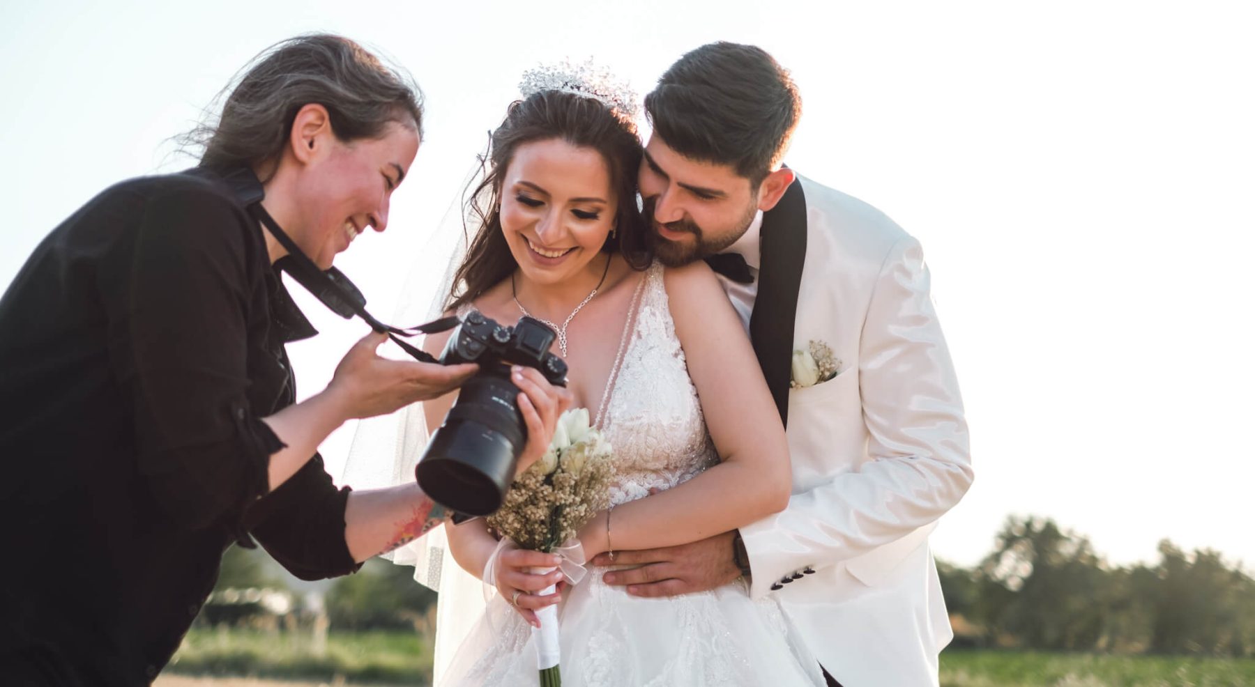 Photographer showing her camera to bride and groom