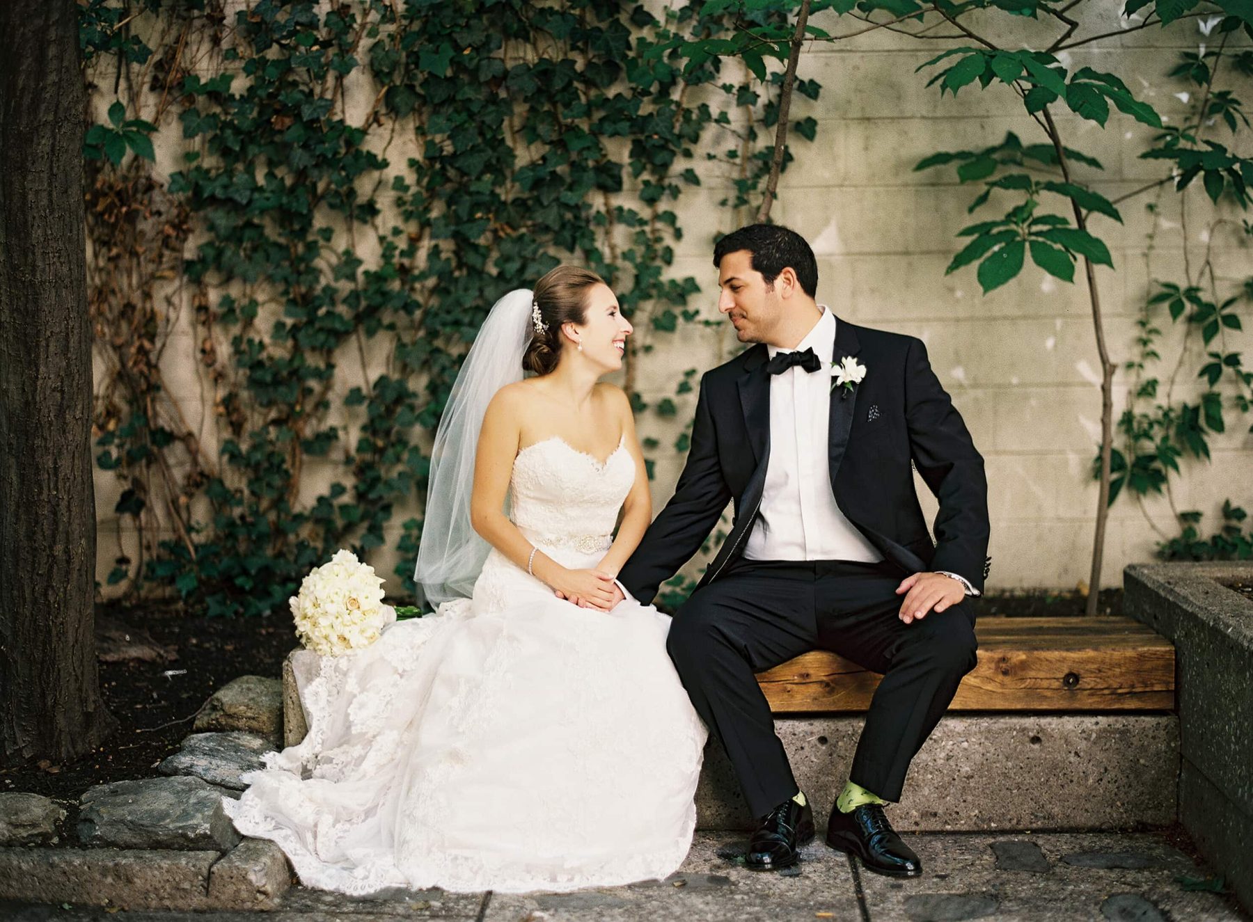 Bride and groom sitting outside on a bench