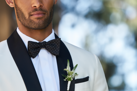 Groom in black and white suit wearing bowtie