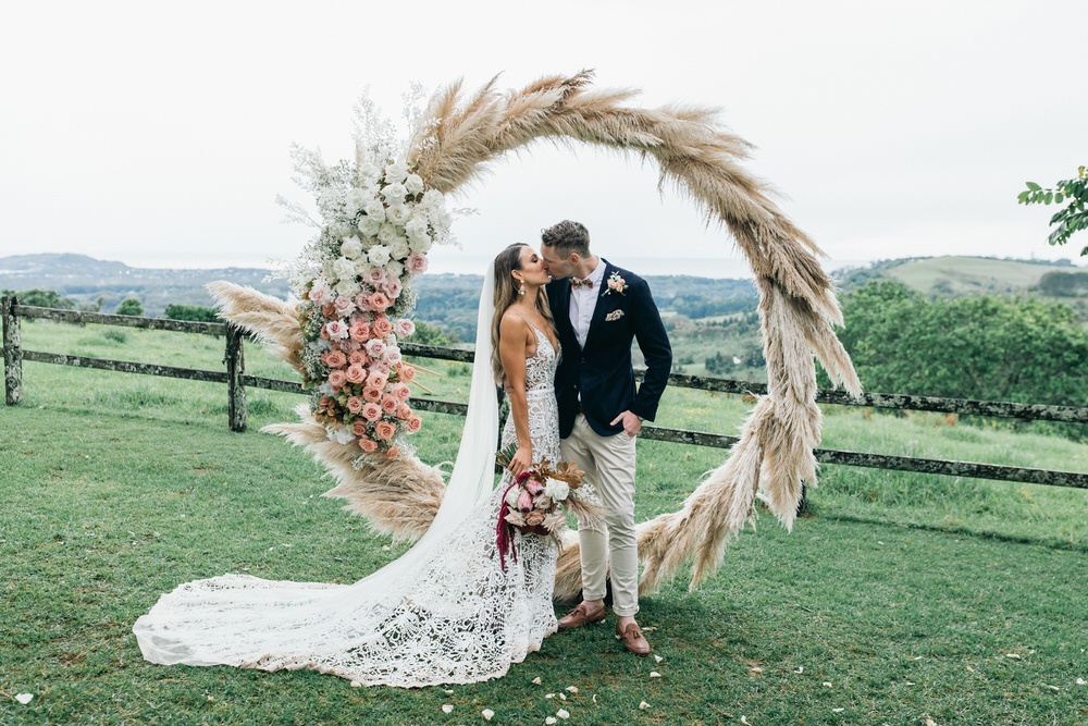Bride and Groom kissing under dried flower arch