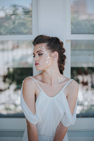 A golden Grecian bridal inspiration shoot styled with a modern braid, a simple baby's breath bouquet and small flakes of gold adorning the bride's face by Blue Rose Studio