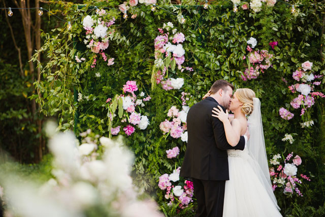 A chic black and white garden wedding in Raleigh featuring a stylish striped motif and a flower wall by Ginny Corbett Photography